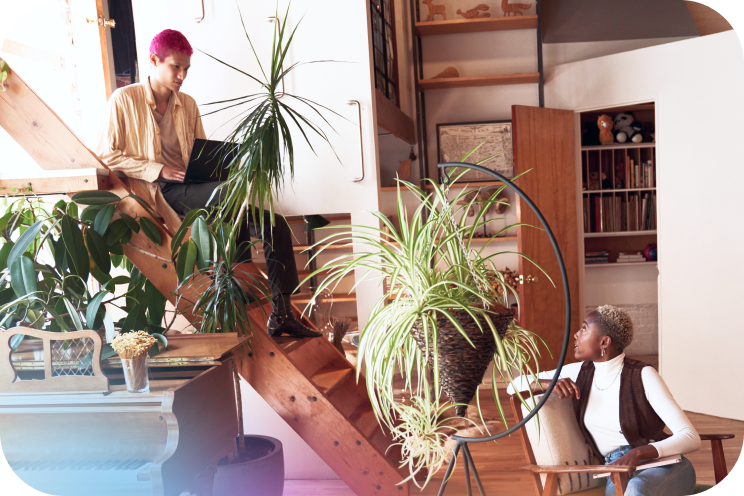 A person sitting on stairs with a laptop talking to another person
