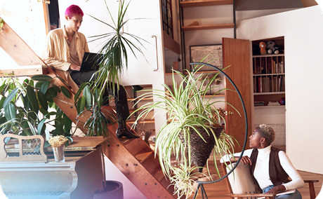 A person sitting on stairs with a laptop talking to another person